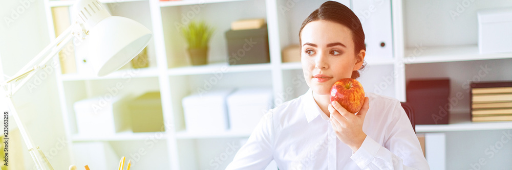 Young girl in the office working with documents and holding an apple. Young girl in the office working with documents and holding an apple.