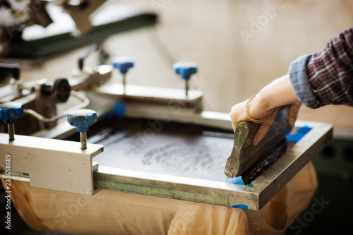 Cropped image of woman pressing ink on frame in workshop