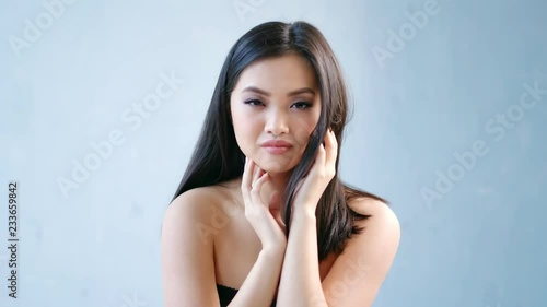Portrait of cute amazing Asian woman looking at camera on gray background