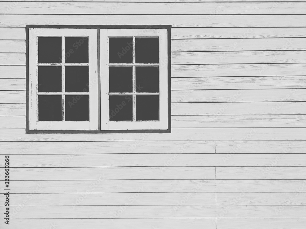 The old white wooden windows on white artificial wood wall background in black and white on film tone and vintage style