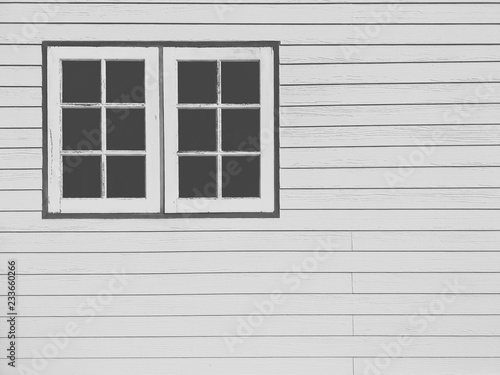 The old white wooden windows on white artificial wood wall background in black and white on film tone and vintage style