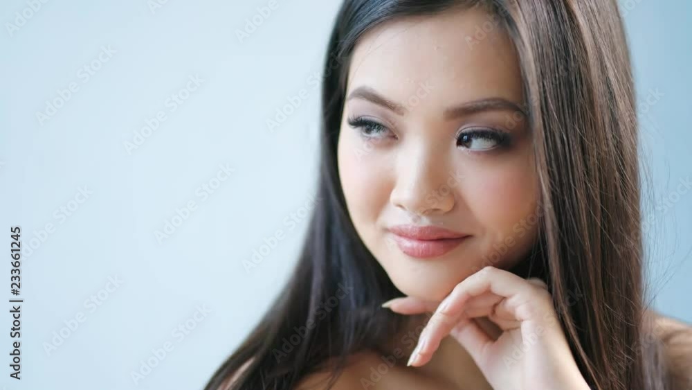 Modest beautiful Korean female having long lashes and big hazel eyes smiling and looking at camera Modest beautiful Korean female having long lashes and big hazel eyes smiling and looking at camera