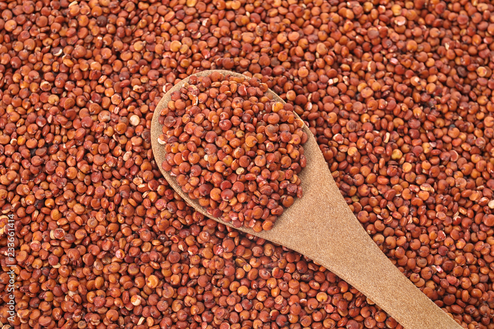 Raw red quinoa seeds with spoon as background, top view Raw red quinoa seeds with spoon as background, top view