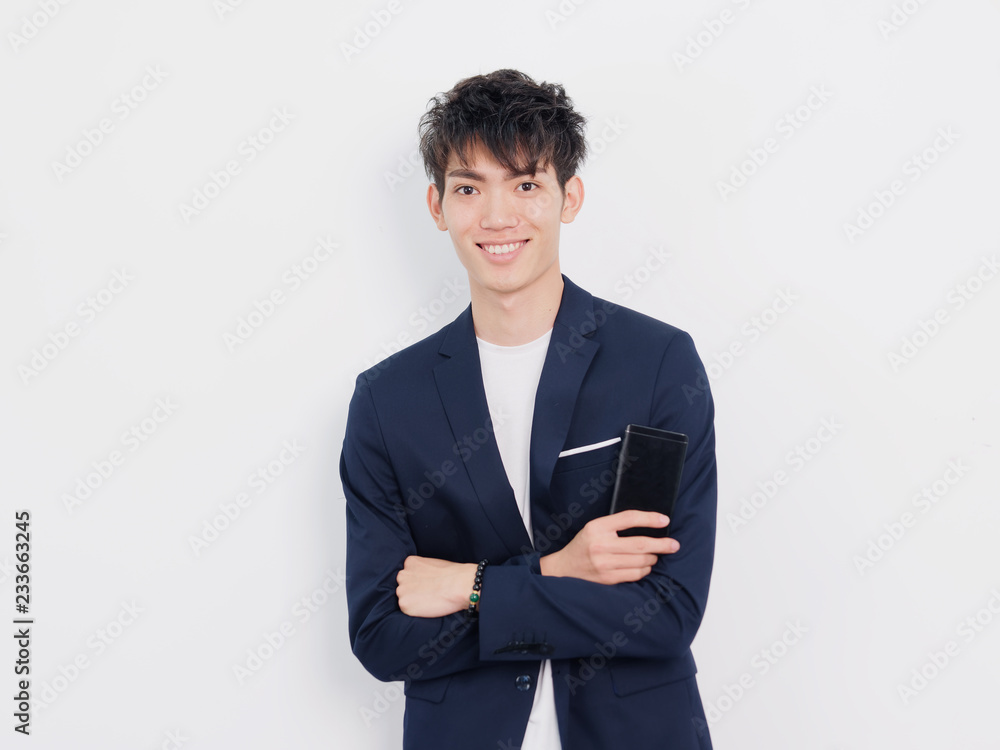 Portrait of handsome Chinese young man in dark blue leisure suit posing against white wall background. Smiling with arms crossed, looks confidence. Portrait of handsome Chinese young man in dark blue leisure suit posing against white wall background. Smiling with arms crossed, looks confidence.