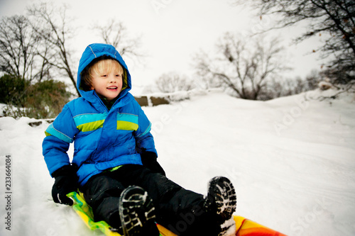 Canvas Print Boy sledding on snow covered field