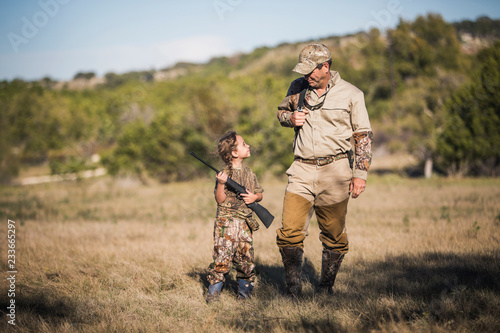 Canvas-taulu Girl holding rifle while looking at father on field