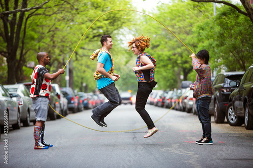Canvas-taulu Friends performing double Dutch on street amidst trees