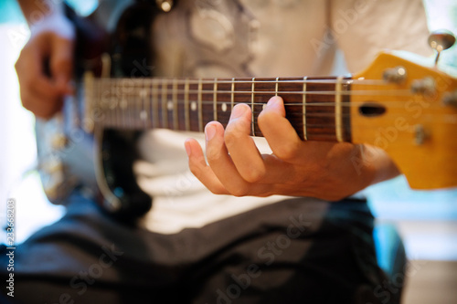 Midsection of teenager practicing electric guitar at home