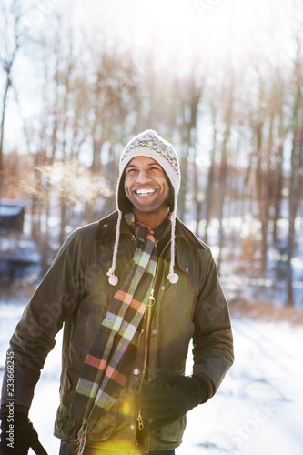 Happy man looking away while standing on snow covered field