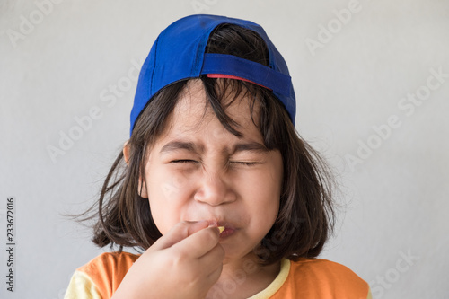 Cute  girl tasting sour lemon.