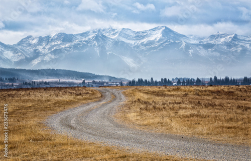 A winding path at the foothills of the Canadian Rockies leads to the majestic snow covered mountains photo