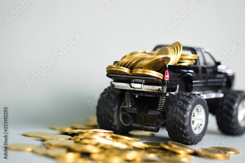 Miniature car pickup truck with stacks of coins on grey background with copy space, banking savings money and business finance concept.