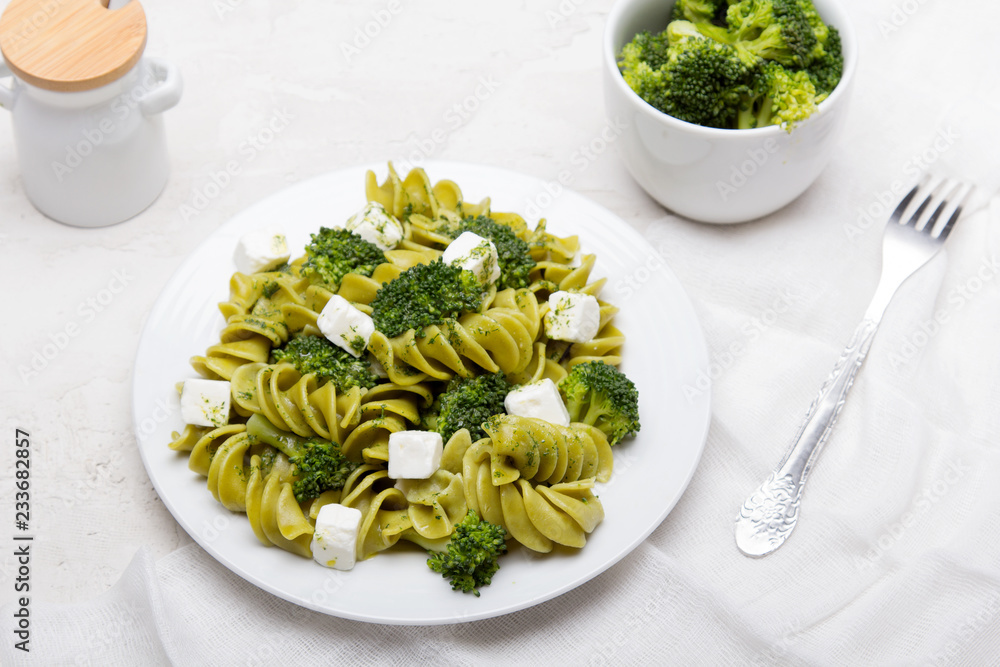 Tasty dinner. Green pasta with broccoli, feta cheese and herb sauce on a white background. Tasty dinner. Green pasta with broccoli, feta cheese and herb sauce on a white background.