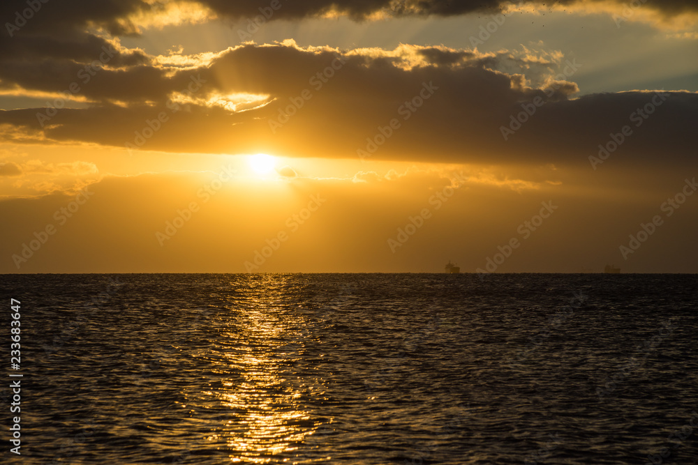Naklejka premium 雲の間から、海を照らす朝日