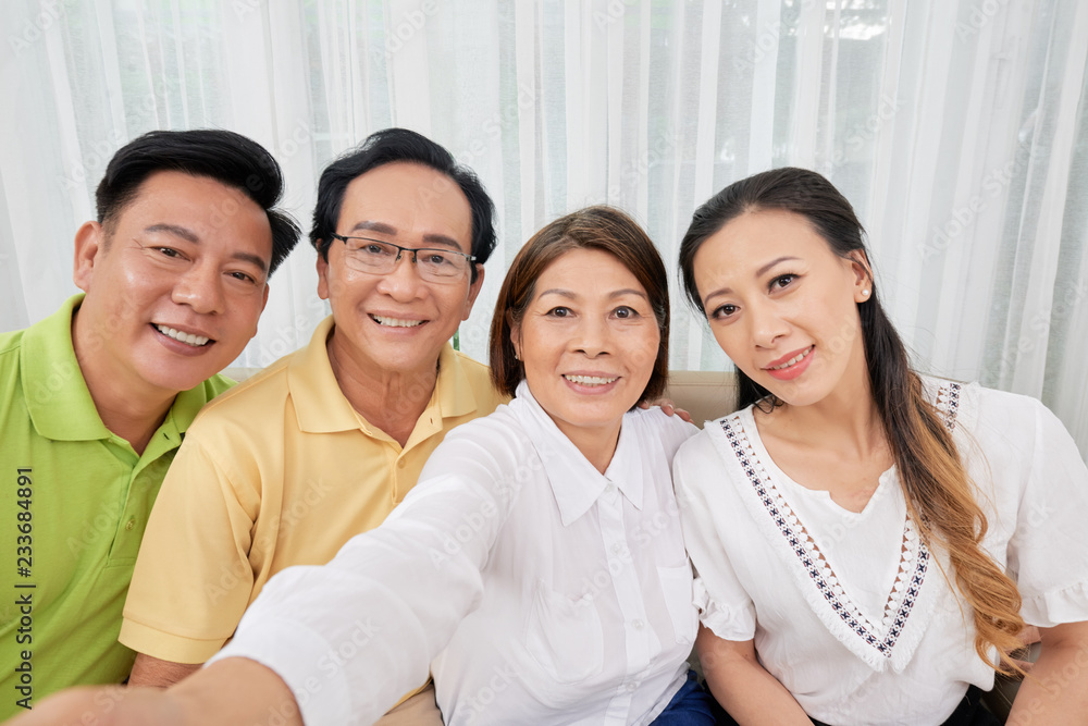 Happy senior Asian woman taking selfie with husband and two adult children Happy senior Asian woman taking selfie with husband and two adult children