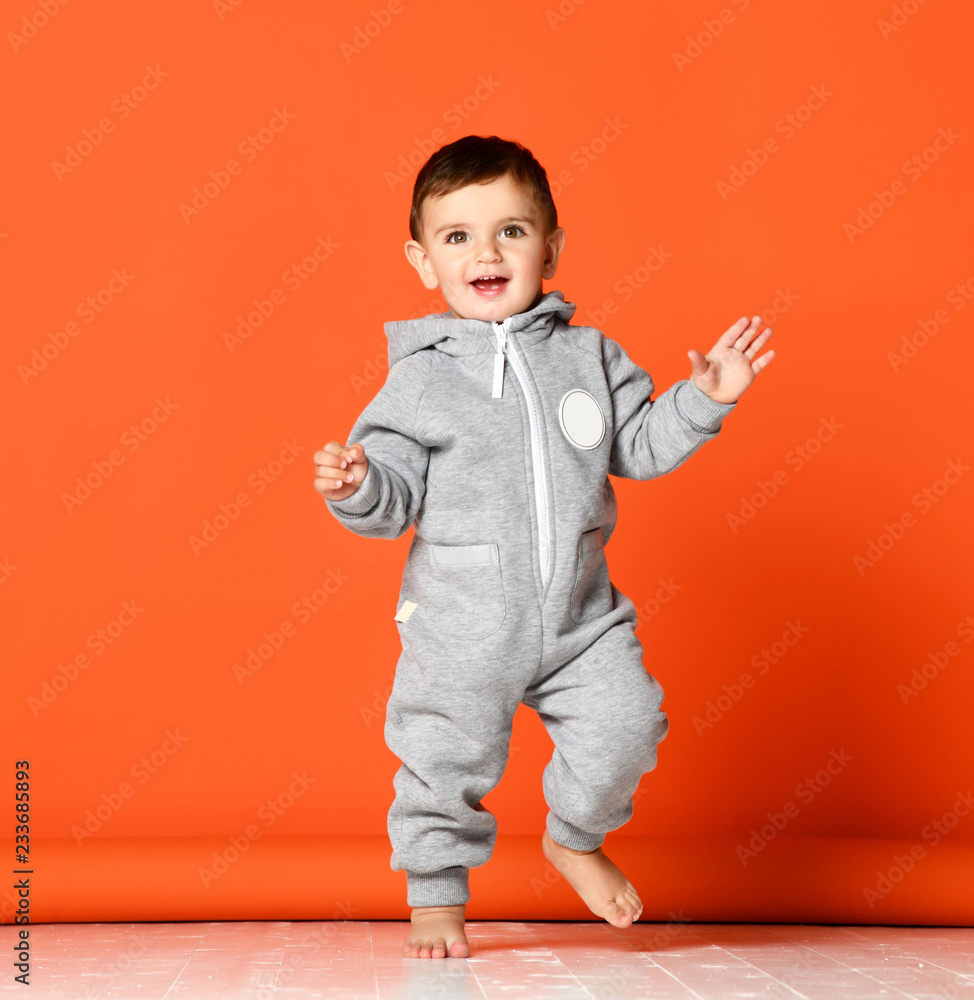 Infant child baby boy kid toddler in light gray body cloth make first steps