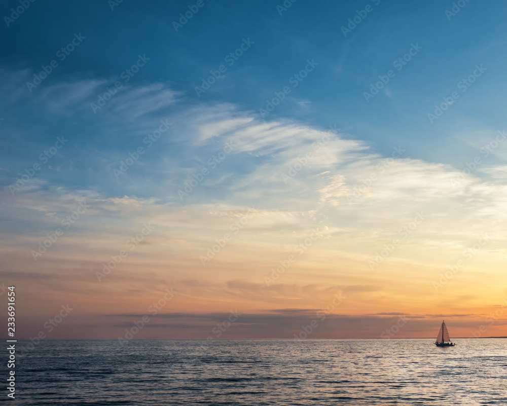 Beautiful gold sunset with a sailboat sailing. Air clouds of different colors.