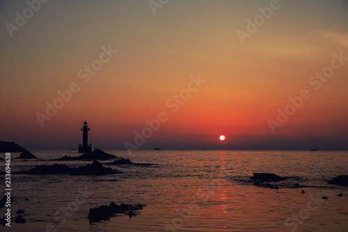 Sunrise scenery on the beach with a lighthouse © SUNGYOON