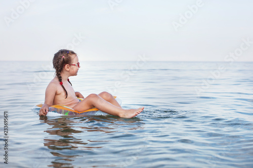 young beautiful girl swims on а rubber ring on the sea