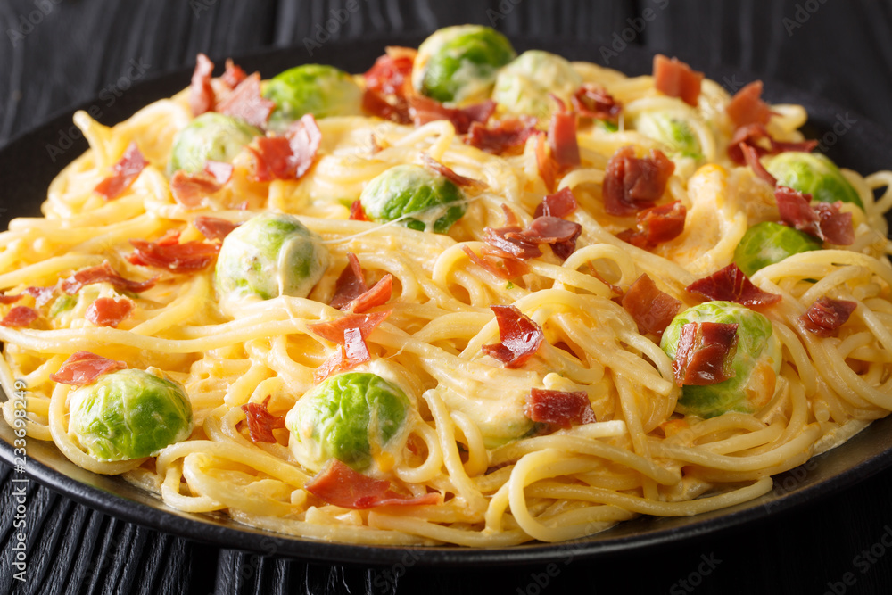 Pasta with Brussels sprouts, ham covered with creamy cheese sauce close-up on a plate. horizontal