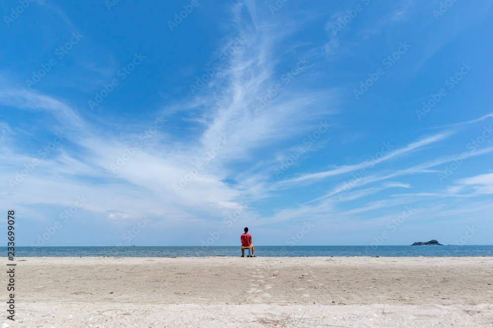 Man on the beach with big blue sky.