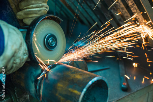 Fotografija mechanic cleans a welded seam on a section of a steel pipe with the help of a gr