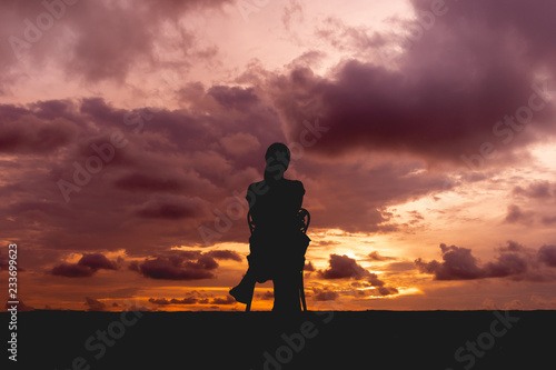 Silhouette of a woman sit on a chair with colorful dramatic sky.