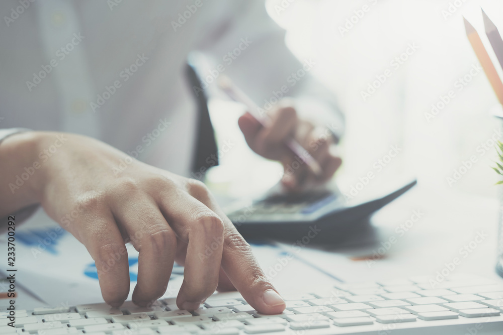 Close up of businessman or accountant hand holding pen working on calculator to calculate business data, accountancy document and laptop computer at office, business concept Close up of businessman or accountant hand holding pen working on calculator to calculate business data, accountancy document and laptop computer at office, business concept