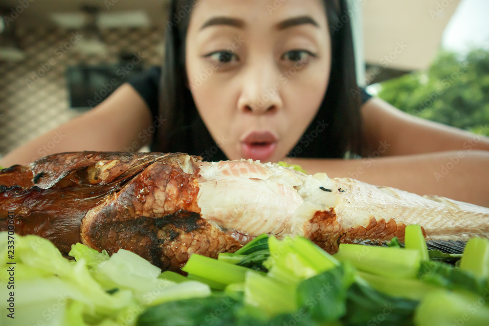 Happy woman with wow face look at grilled fish.