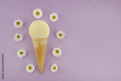 bath Bomb with chamomile extract. yellow bath bombs with chamomile flowers in a waffle cone for ice cream on a light purple background. Organic Pure Vegetable Body Cosmetics Concept