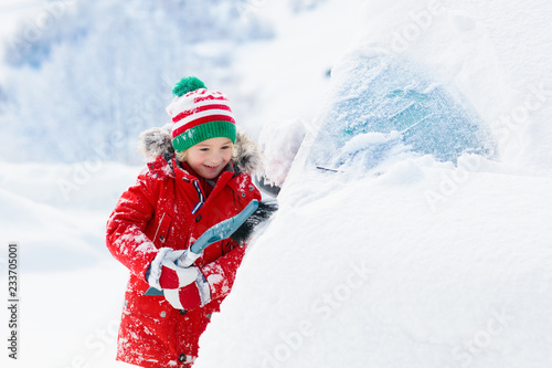 Child brushing off car. Kid with winter snow brush