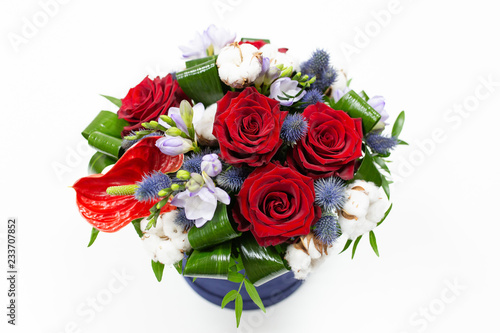 A bright bouquet of red flowers  rose and anthurium  with green leaves  Alstroemeria and cotton flowers in a blue box for hats on a light background