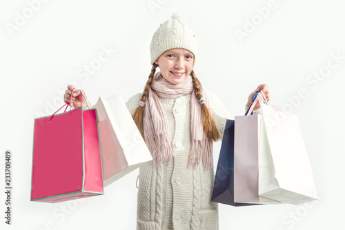 Girl with gift bags on a light background. Shopping before Christmas.