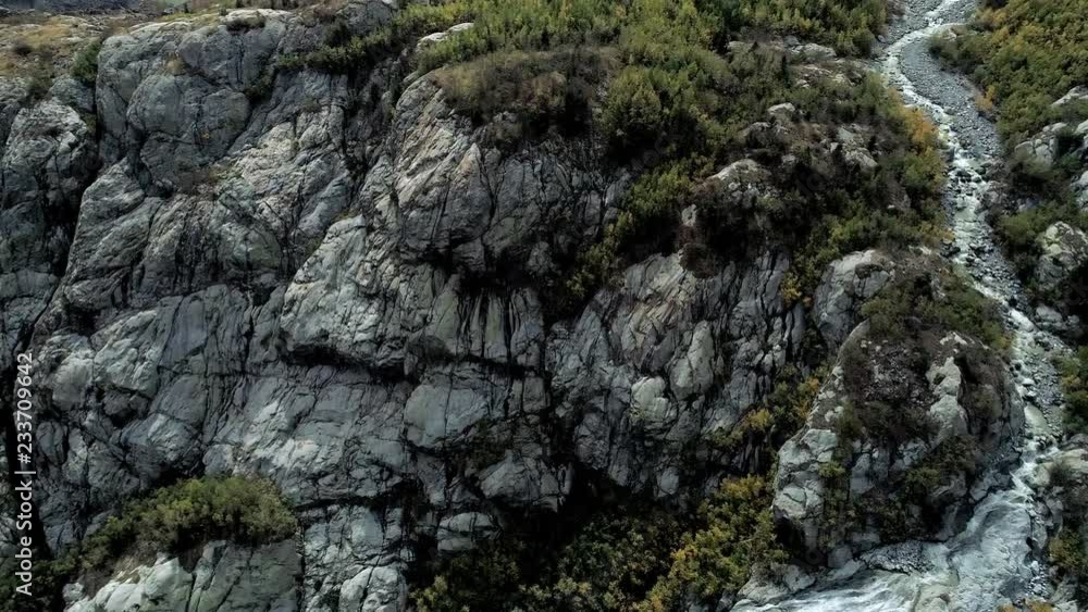 Aerial: mountain waterfall flows over the rocks. Above the huge mountain glacier. Aerial: mountain waterfall flows over the rocks. Above the huge mountain glacier.