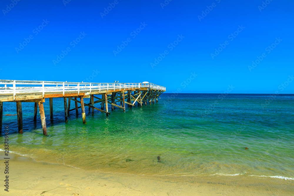 Paradise Cove Pier, a wooden pier in Paradise Cove beach, Malibu, California, United States. Wallpaper turquoise waters, copy space. Luxurious travel destination on Pacific Coast. Summer blue sky.