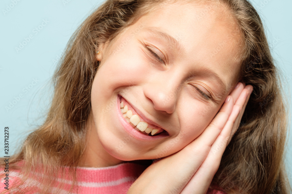 smiling girl pretending to be sleeping using hands as pillow. emotional facial expression. smiling girl pretending to be sleeping using hands as pillow. emotional facial expression.