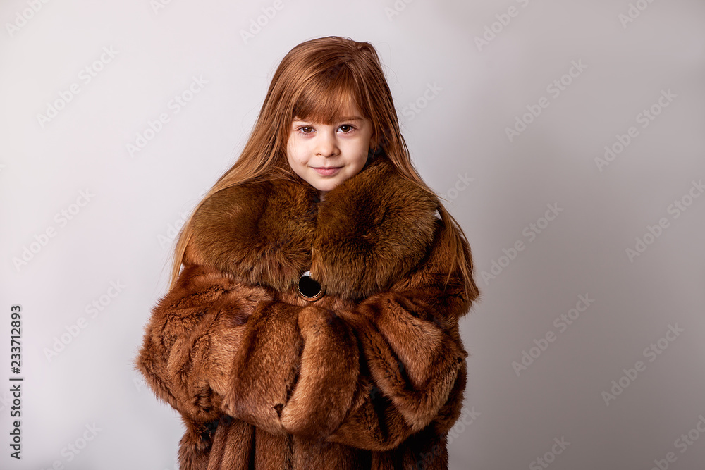A child a girl in her mother s fur coat. Faux fur winter clothes