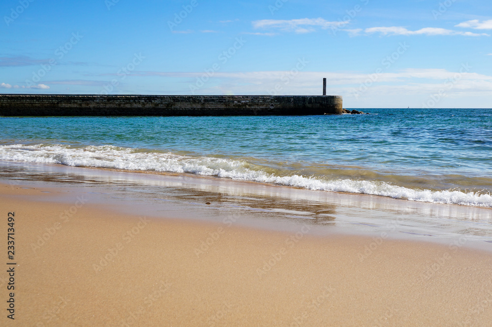 Landscape with golden sand beach and blue sky in the touristic destination Cascais, Portugal. 