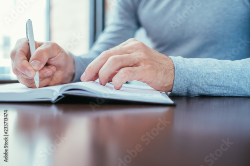 man writing in hid personal organizer. planning and information structuring.