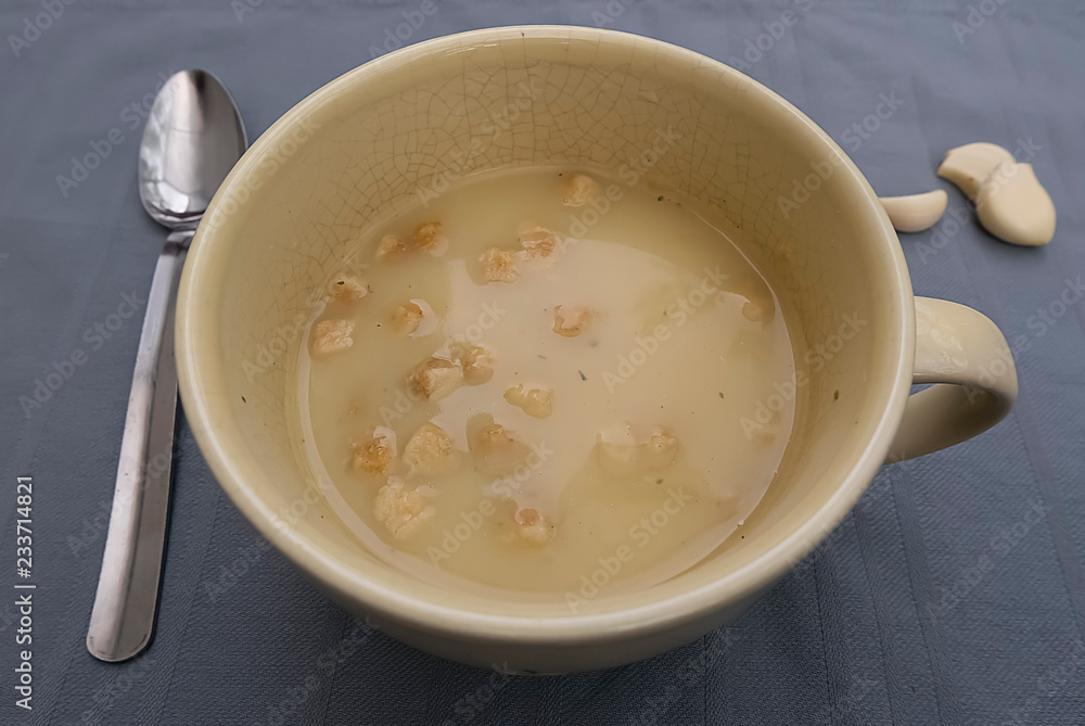 Chicken cream soup with croutons in a yellow cup on a gray background. Chicken cream soup with croutons in a yellow cup on a gray background.