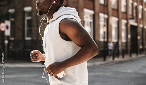 Obraz na plátně Athletic man running with earphones