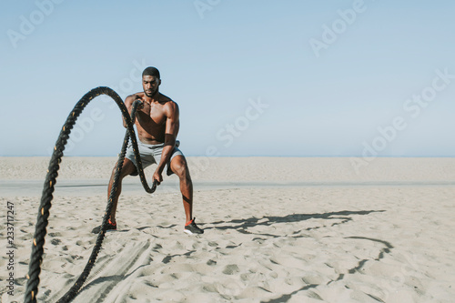 Fit man working out with battle ropes