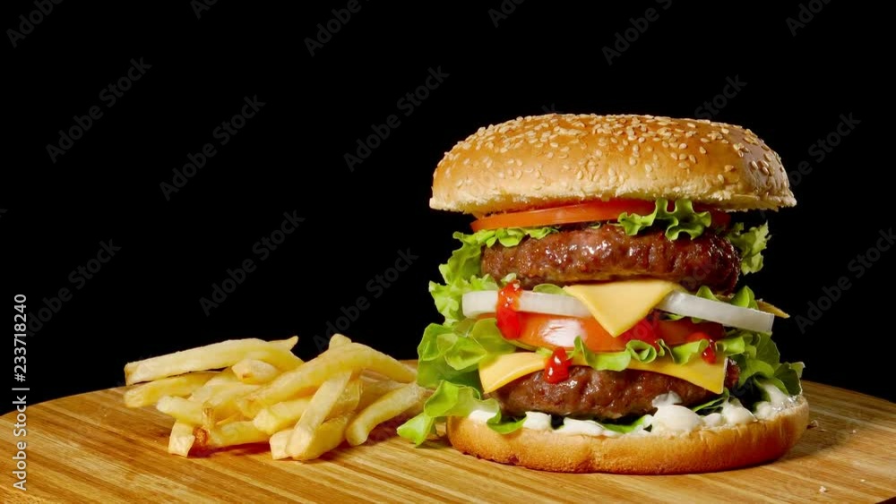 Craft beef burger and french fries on wooden table isolated on black background. Craft beef burger and french fries on wooden table isolated on black background.