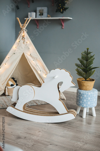 Cozy kids room interior with play tent or wigwam, toy horse and christmas tree