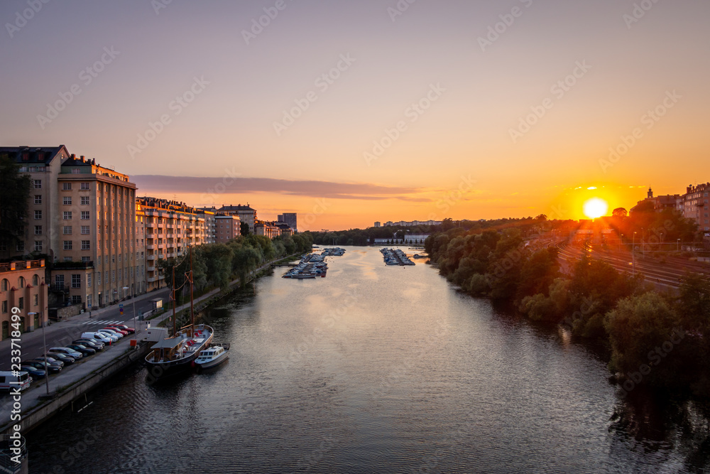 Beautiful golden summer sunset in Stockholm sweden. Perspective of water canal with boats and buildings on the side.