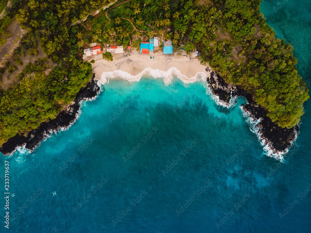 White sand beach with coconut palms and crystal blue ocean in Bali. Aerial view