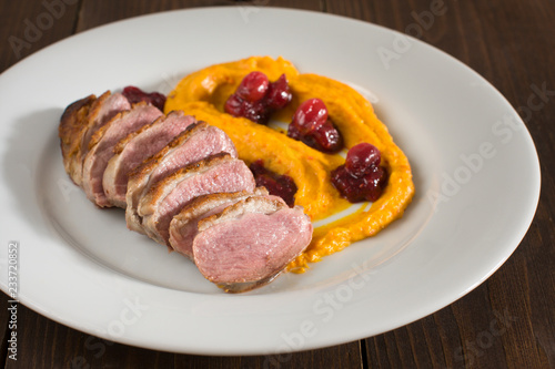 closeup of a duck breasts with squash puree and cranberries