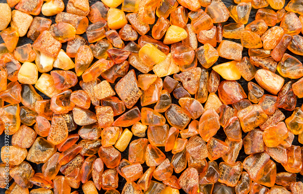 Whole background covered with chips of orange baltic amber. The Baltic region is home to the largest known deposit of amber, called Baltic amber or succinite. - obrazy, fototapety, plakaty 