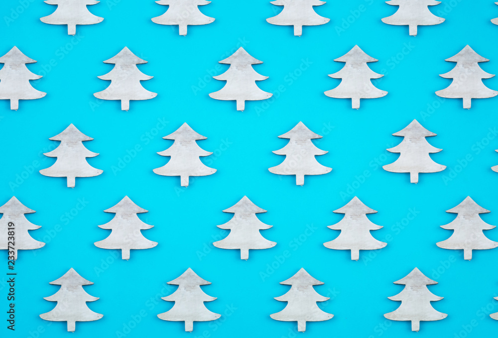 Creative and minimal  Christmas pattern made of wooden christmas trees. Blue background. Flat lay top view.
