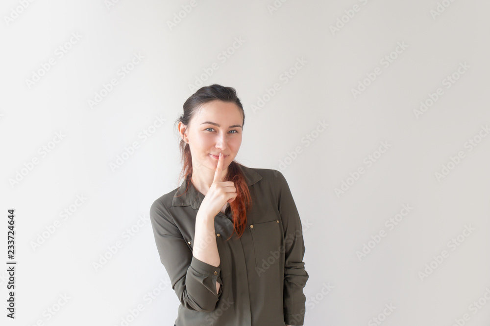 Happy pretty Caucasian woman holding finger near mouth and smiling. Young female colleague asking to keep secret about surprise party. Silence concept Happy pretty Caucasian woman holding finger near mouth and smiling. Young female colleague asking to keep secret about surprise party. Silence concept